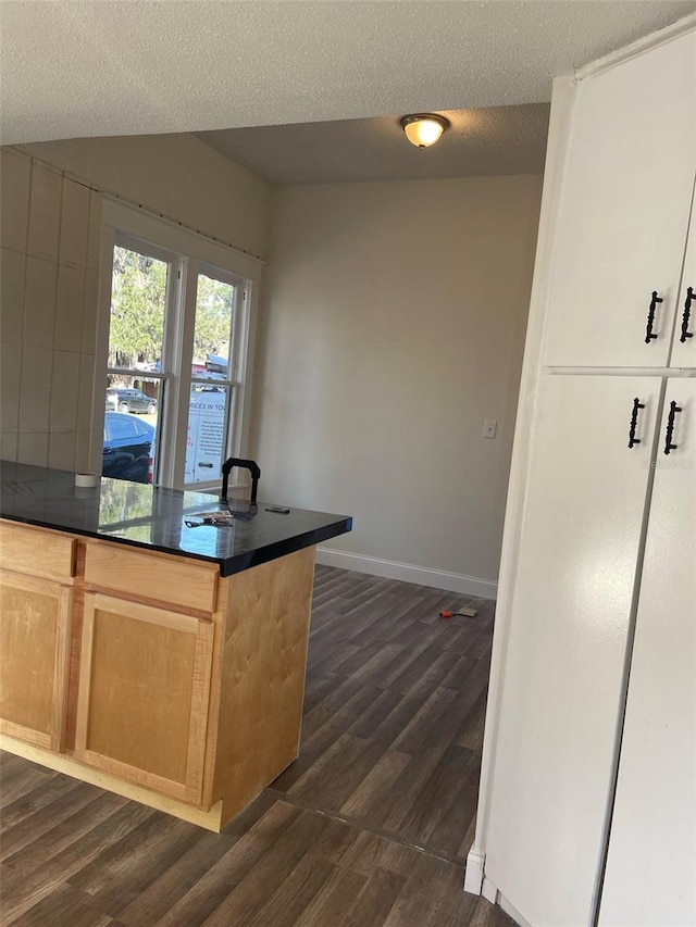 kitchen with light brown cabinetry, a textured ceiling, white cabinetry, and dark wood-type flooring