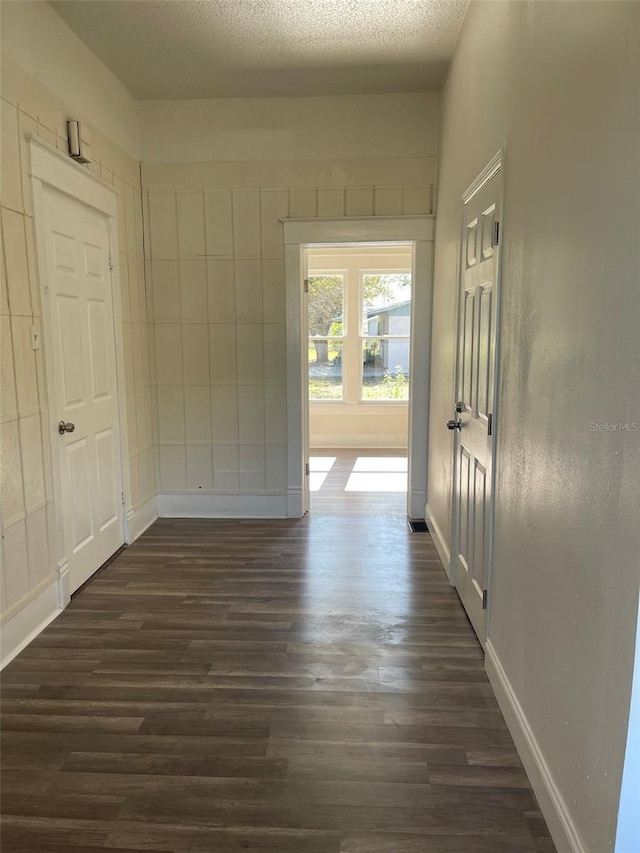 hallway with dark hardwood / wood-style flooring and a textured ceiling