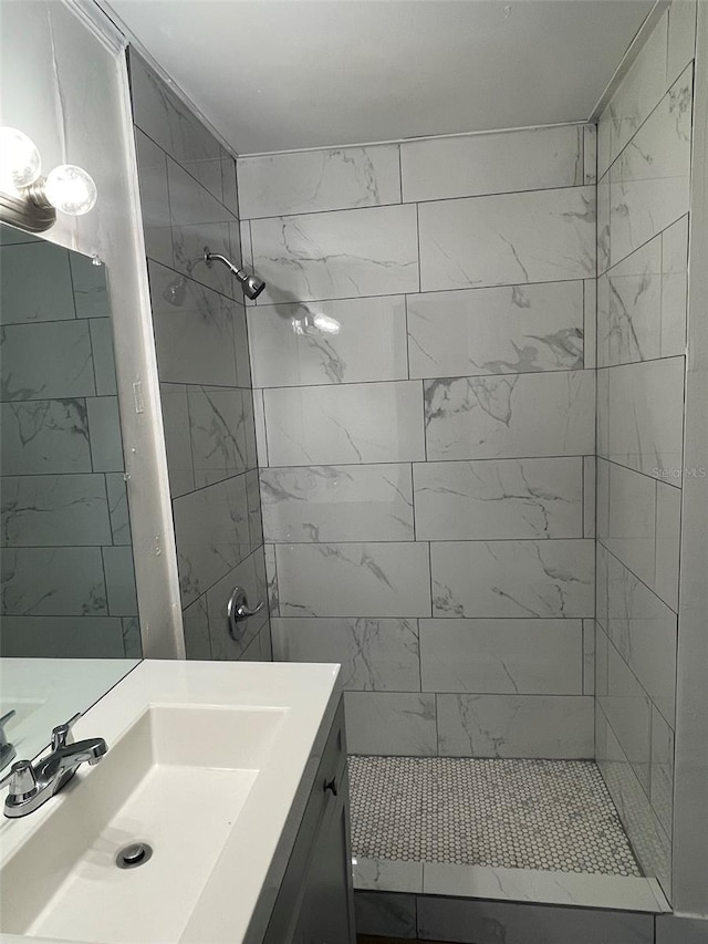 bathroom with tiled shower and large vanity