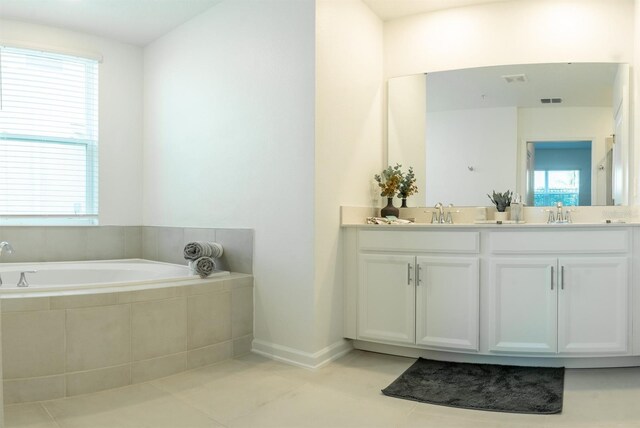 bathroom featuring a relaxing tiled bath, tile flooring, double sink, and a wealth of natural light