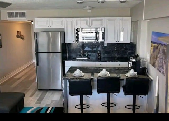 kitchen featuring a breakfast bar, tasteful backsplash, appliances with stainless steel finishes, white cabinets, and sink