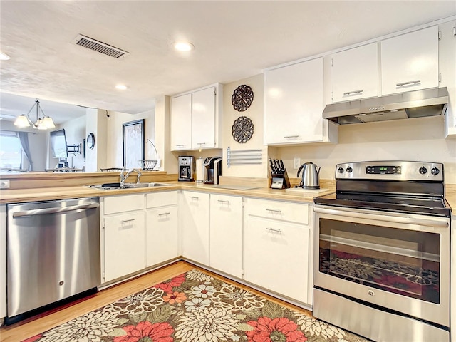1513 Ocean Shore Blvd Unit 9E, Ormond Beach, FL 32176 - kitchen featuring light wood-style flooring, appliances with stainless steel finishes, light countertops, under cabinet range hood, and visible vents