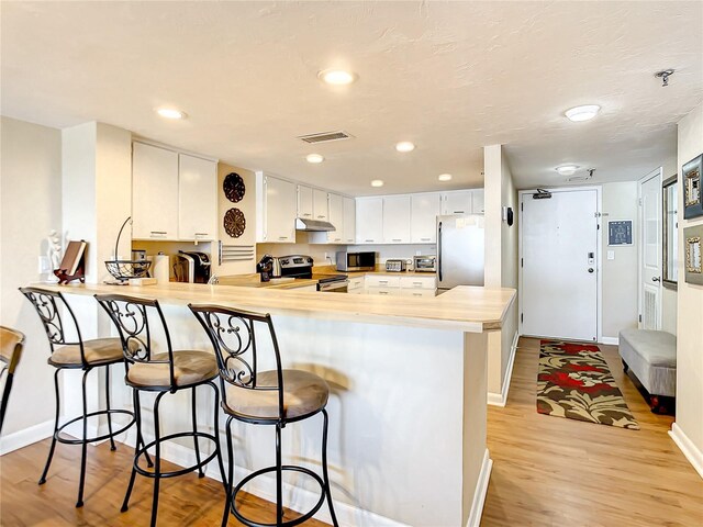 1513 Ocean Shore Blvd Unit 9E, Ormond Beach, FL 32176 - kitchen featuring a peninsula, visible vents, light countertops, under cabinet range hood, and appliances with stainless steel finishes