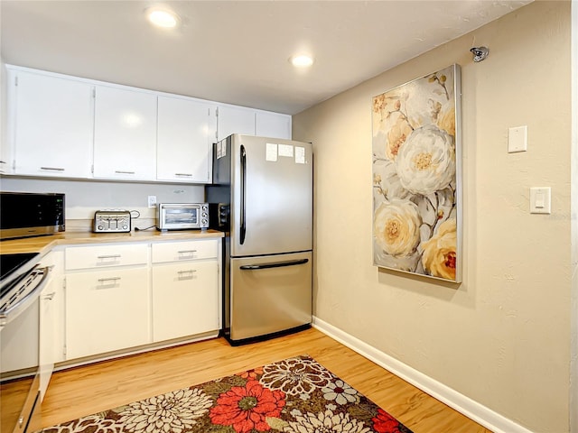 1513 Ocean Shore Blvd Unit 9E, Ormond Beach, FL 32176 - kitchen with light wood-style floors, light countertops, white cabinets, baseboards, and appliances with stainless steel finishes