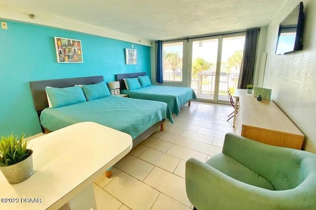 tiled bedroom featuring access to exterior, floor to ceiling windows, multiple windows, and a textured ceiling