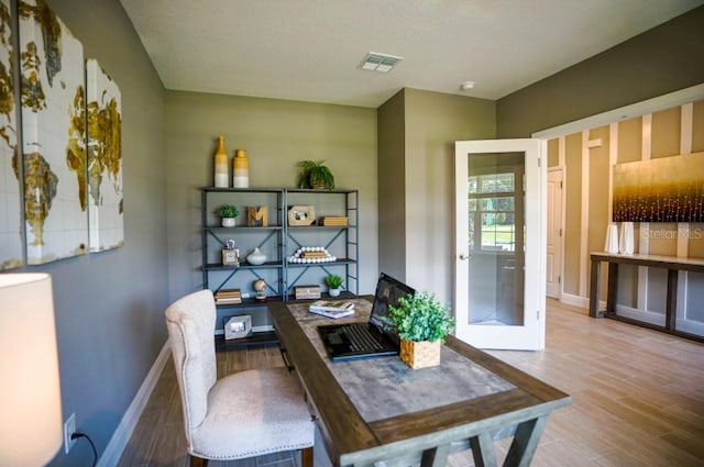 dining space with visible vents, baseboards, wood finished floors, and french doors