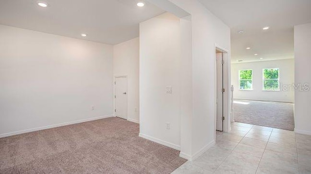 empty room featuring recessed lighting, baseboards, light colored carpet, and light tile patterned floors