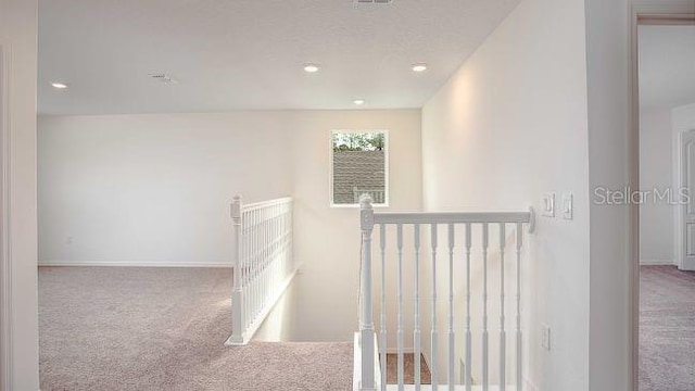 hall with recessed lighting, baseboards, an upstairs landing, and carpet flooring