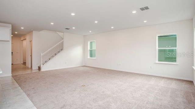 unfurnished living room featuring visible vents, baseboards, stairs, light carpet, and recessed lighting