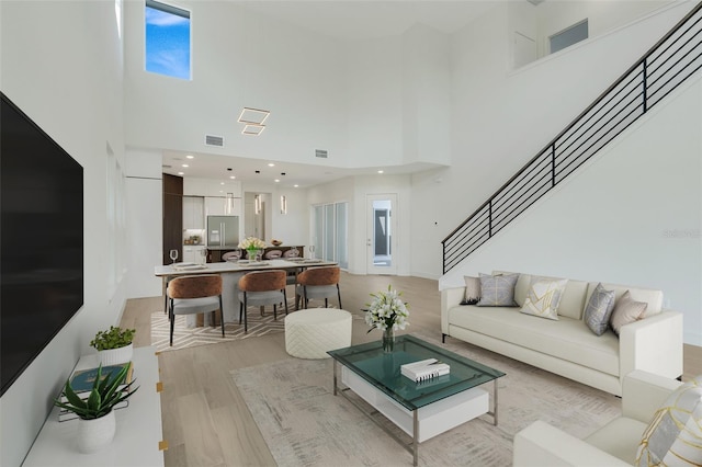 living room featuring a towering ceiling and light wood-type flooring