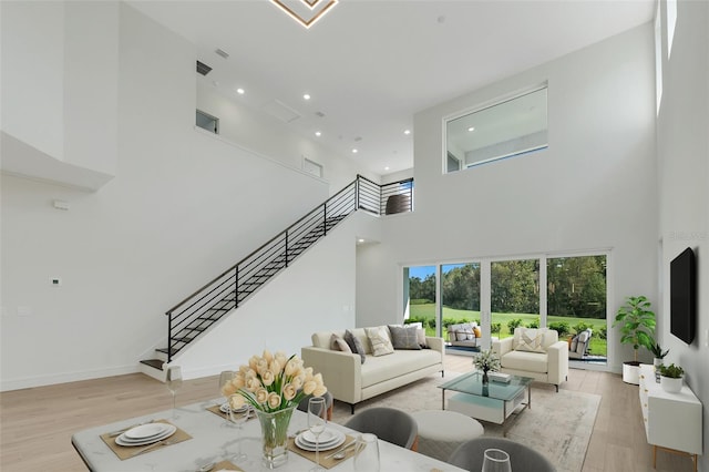 living room with light hardwood / wood-style floors and a towering ceiling