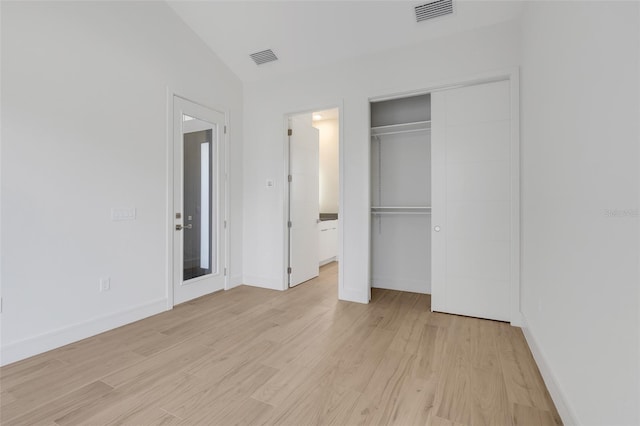 unfurnished bedroom featuring lofted ceiling, a closet, and light hardwood / wood-style floors