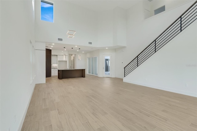 unfurnished living room with light hardwood / wood-style flooring and a high ceiling