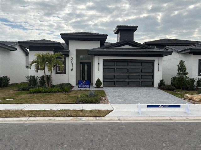 3016 Kensington Ave, Davenport, FL 33837 - prairie-style house featuring decorative driveway, a garage, and stucco siding