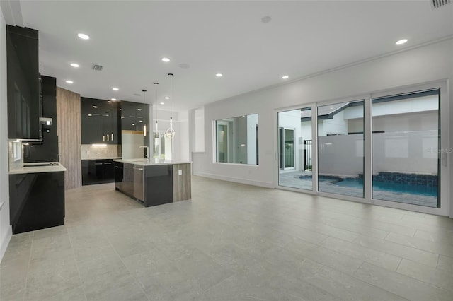 kitchen featuring decorative light fixtures, sink, a center island with sink, and backsplash