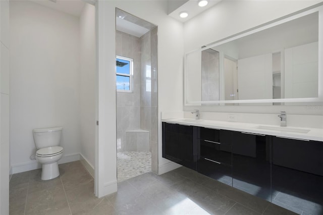 bathroom featuring vanity, toilet, and a tile shower