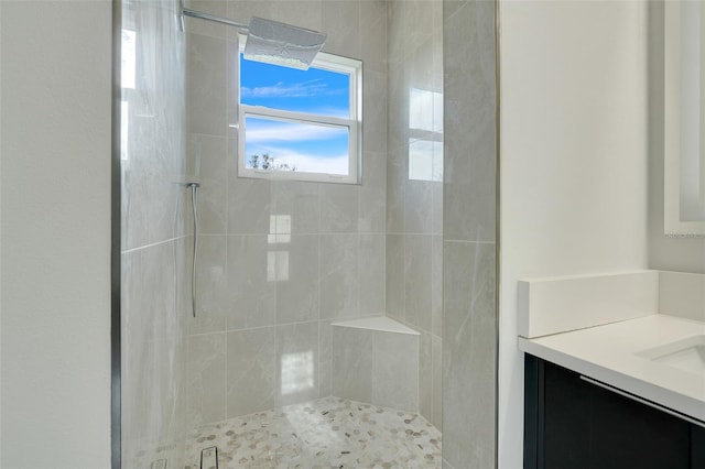 bathroom featuring tiled shower and vanity