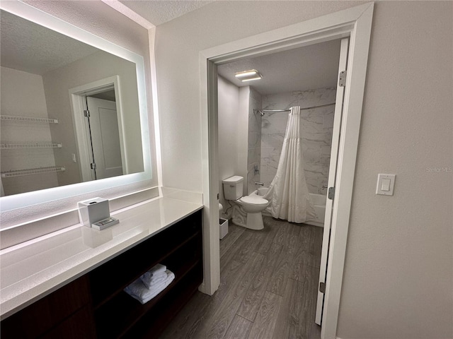 full bathroom featuring toilet, hardwood / wood-style flooring, shower / bathtub combination with curtain, vanity, and a textured ceiling