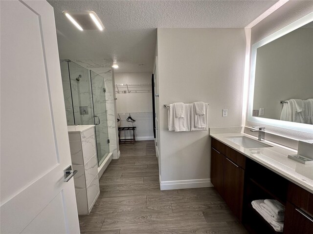 bathroom featuring hardwood / wood-style floors, a textured ceiling, vanity, and a shower with shower door