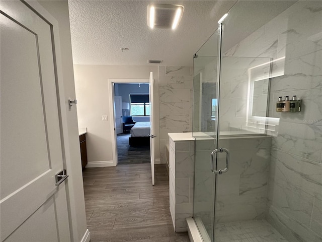 bathroom with a textured ceiling, a shower with door, wood-type flooring, and vanity