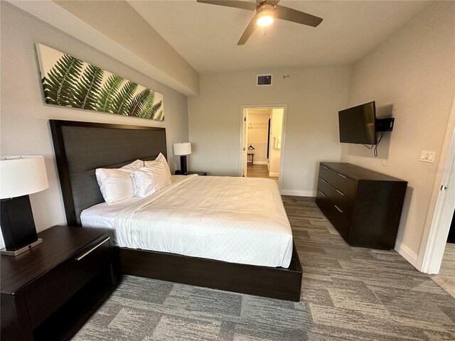 bedroom with dark colored carpet, ceiling fan, and ensuite bathroom