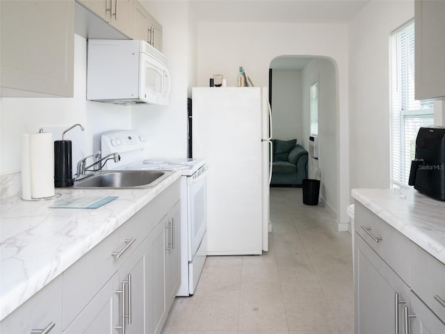 kitchen featuring light tile floors, white appliances, sink, and light stone counters