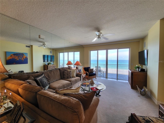 living room featuring light colored carpet, a textured ceiling, ceiling fan, and a water view