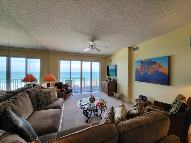 carpeted living room with a water view, ceiling fan, and a textured ceiling