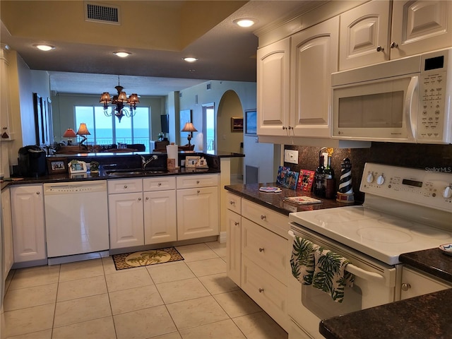 kitchen featuring white appliances, a notable chandelier, white cabinetry, and a wealth of natural light