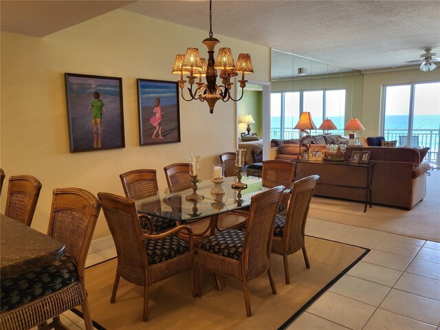 tiled dining room with a water view, a textured ceiling, and ceiling fan with notable chandelier