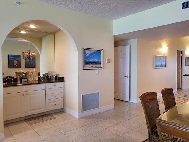 interior space with vanity, a textured ceiling, tile floors, and a chandelier