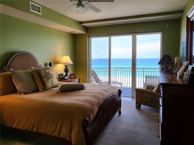 bedroom with a water view, access to exterior, and a textured ceiling