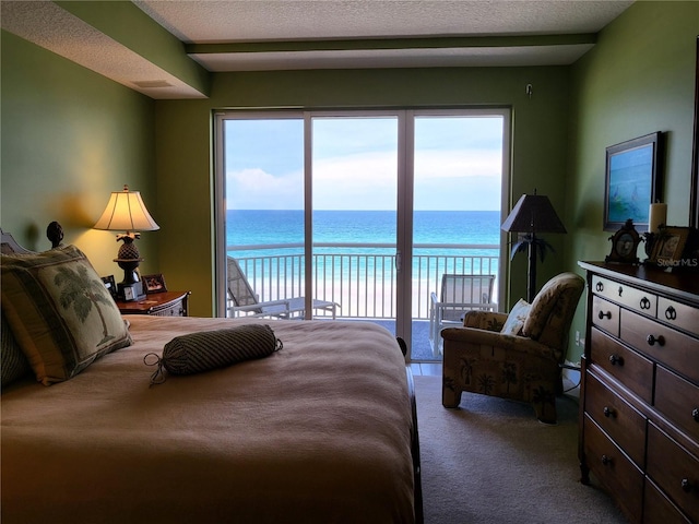 carpeted bedroom with a water view, access to exterior, and a textured ceiling