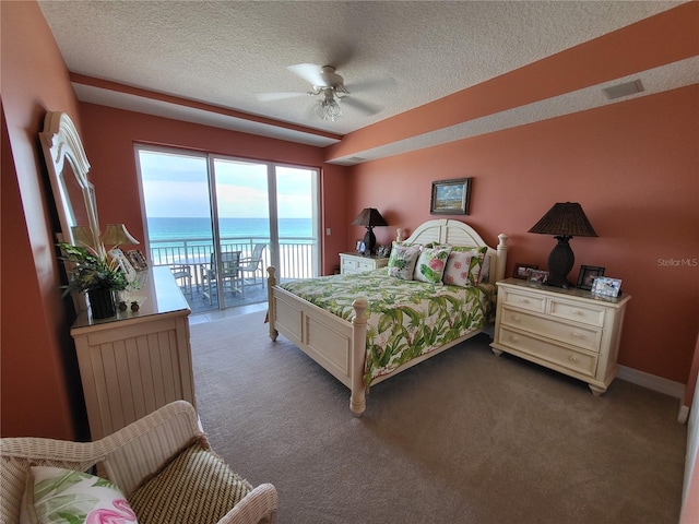 bedroom featuring ceiling fan, a textured ceiling, access to exterior, and a water view