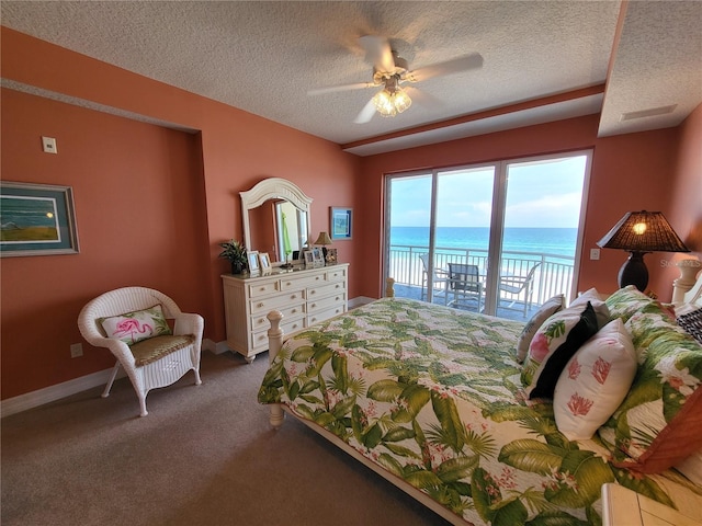 carpeted bedroom featuring a water view, a textured ceiling, ceiling fan, and access to outside