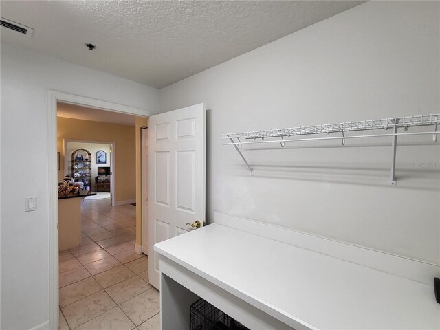 interior space featuring a textured ceiling and light tile flooring