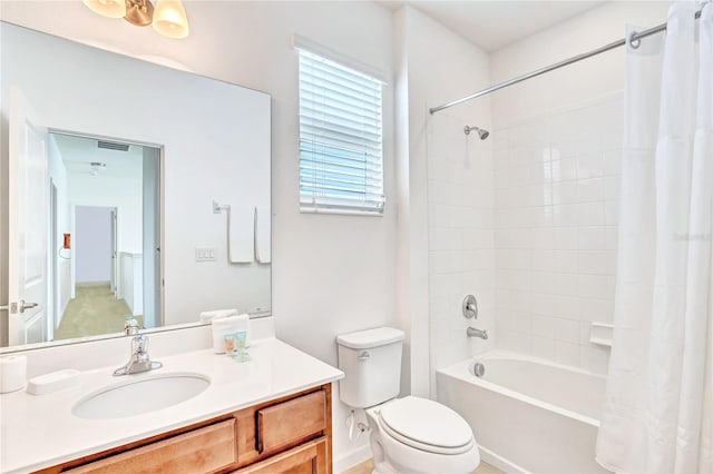 full bathroom featuring shower / tub combo with curtain, vanity with extensive cabinet space, and toilet