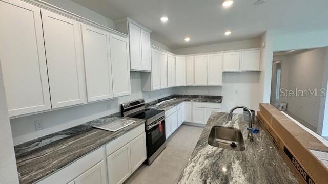 kitchen featuring sink, white cabinetry, stainless steel range with electric stovetop, and dark stone countertops