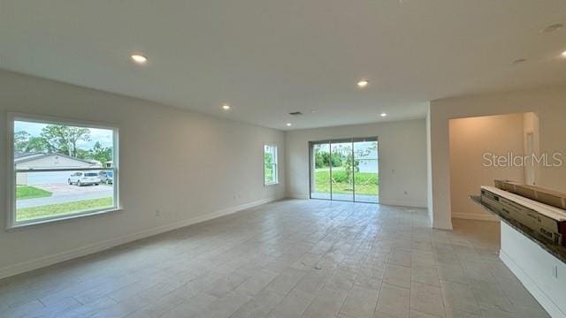 unfurnished living room featuring recessed lighting and baseboards