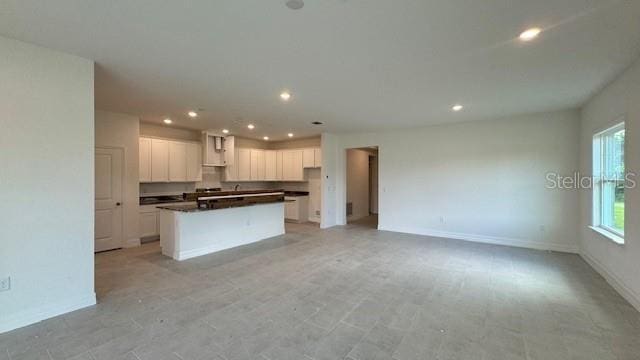 kitchen featuring dark countertops, recessed lighting, open floor plan, white cabinets, and a kitchen island