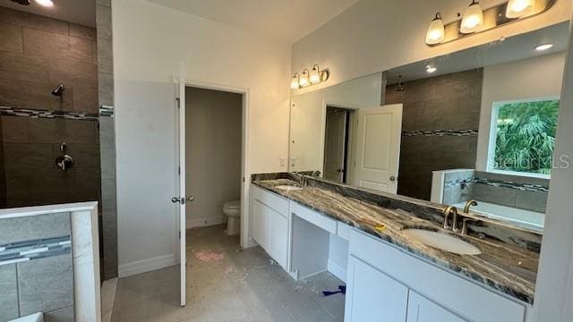 full bath with toilet, double vanity, a sink, and a bath