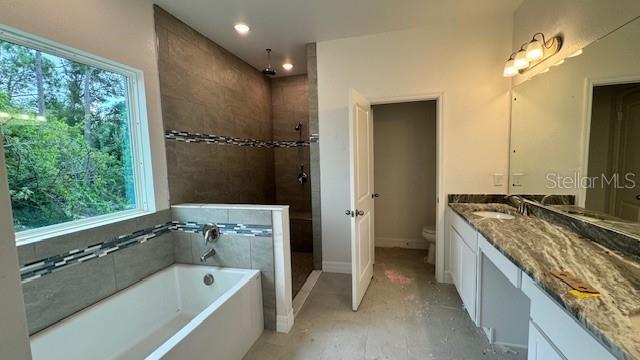 full bathroom featuring a garden tub, toilet, vanity, baseboards, and a tile shower