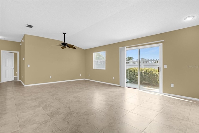 spare room featuring light tile floors, lofted ceiling, a textured ceiling, and ceiling fan