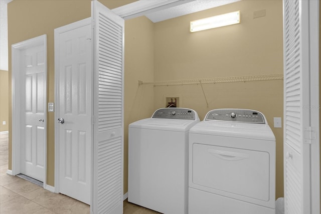 clothes washing area featuring light tile floors, washer hookup, and washing machine and dryer