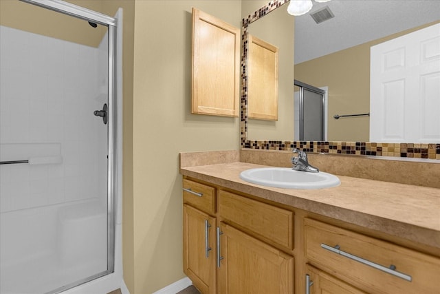 bathroom featuring backsplash, a textured ceiling, vanity, and a shower with door