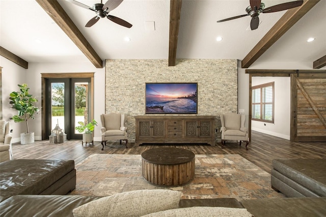 living room featuring a barn door, beam ceiling, ceiling fan, and a wealth of natural light