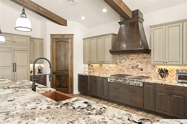 kitchen with decorative light fixtures, vaulted ceiling with beams, light wood-type flooring, premium range hood, and light stone counters