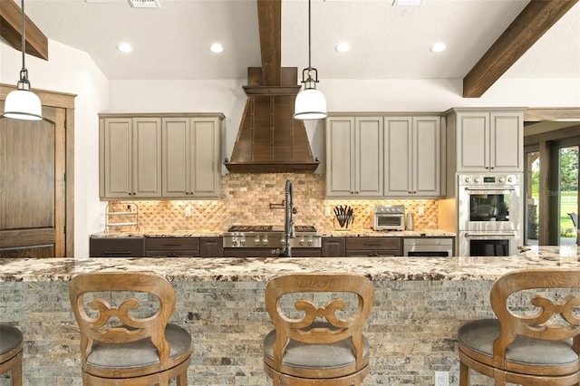 kitchen featuring stainless steel double oven, pendant lighting, a breakfast bar, and light stone counters