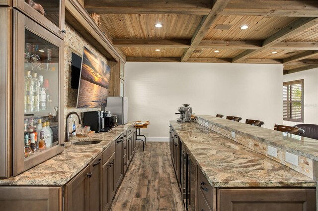 kitchen with coffered ceiling, dark hardwood / wood-style floors, beamed ceiling, light stone counters, and wood ceiling