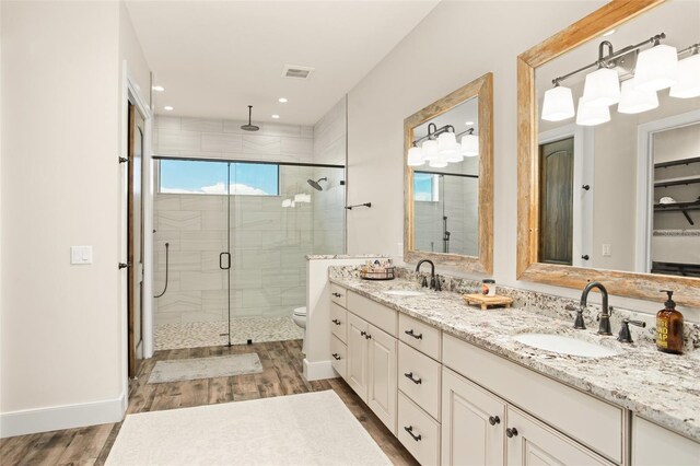 bathroom featuring toilet, hardwood / wood-style floors, dual vanity, and walk in shower